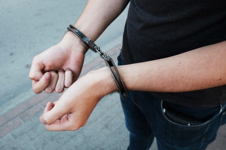 Young Offender In Handcuffs On Wrists Standing On Street